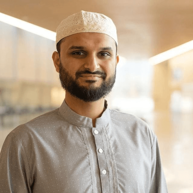 Imam Shuaib, in a grey thobe and cream kufi